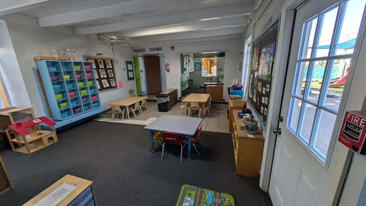 Classroom with cubbies, learning tables and a door onto the playground